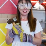 photo of woman in safety glasses and gloves smiling