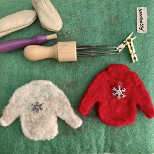 Two needle felted jumper shapes with selection of tools